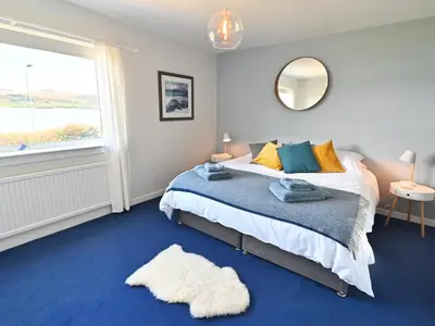 a bedroom with a bed and a mirror and a window at Taigh An Uillt in Tighnabruaich