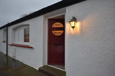 a house with a red door and a light on it at Unique restored Old Post Office in Kinlochleven