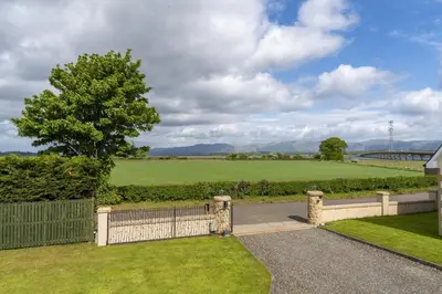 a driveway with a fence and a field at Higginsneuk in Airth