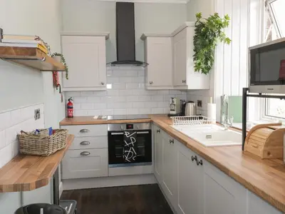 a kitchen with white cabinets and a wooden counter top at 40 Main Street in Burntisland