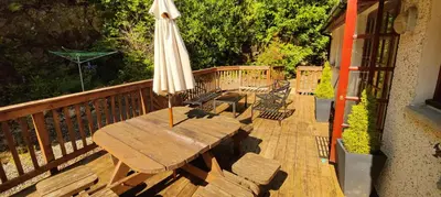 a wooden table with an umbrella on a deck at Ben Reoch Cottage - Loch Lomond and Arrochar Alps in Tarbet