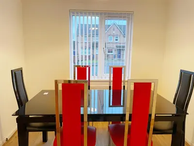 a dining room table with red chairs and a window at Cozy Nights SVP Detached House in Nitshill