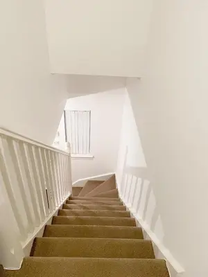 a staircase in a building with white walls and brown stairs at Cozy Nights SVP Detached House in Nitshill
