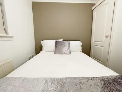 a small bedroom with a bed with white sheets at Cozy Nights SVP Detached House in Nitshill
