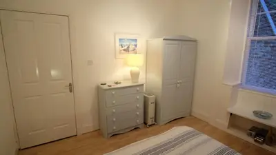 a bedroom with a dresser and a lamp and a door at Tighnabruaich Duplex Apartment - Sea Views in Tighnabruaich