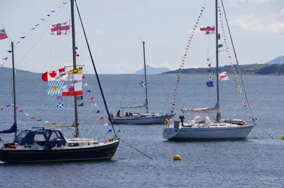 three boats in the water with flags on them at Tighnabruaich Duplex Apartment - Sea Views in Tighnabruaich