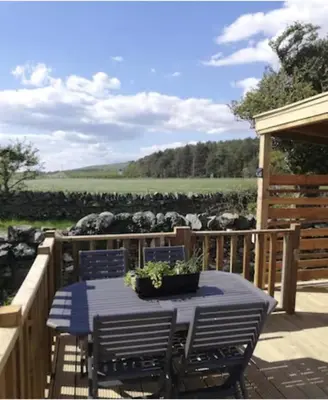 a patio with a table and chairs and a fence at The Galloway Steading- The Bee Hive Couples Retreat with Hot Tub and Fire Pit in Glenluce