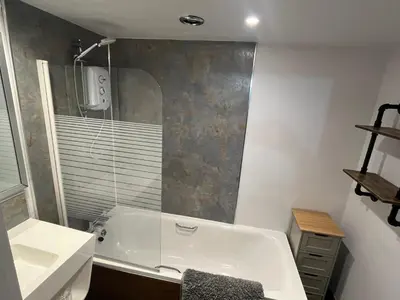 a bathroom with a white tub and a sink at The Mail Barn in Lamlash