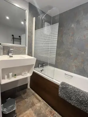 a bathroom with a sink and a tub and a mirror at The Mail Barn in Lamlash