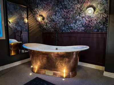 a bath tub in a room with a floral wall at Glencruitten House in Oban