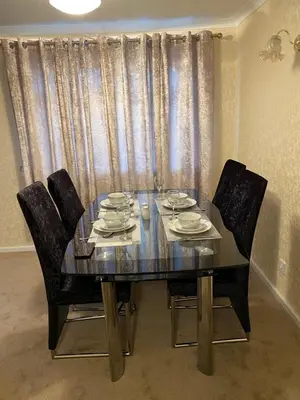 a dining room table with four chairs and a glass table and chairsuggest at Dunfermline, 2 bedroom home free on street parking in Fife