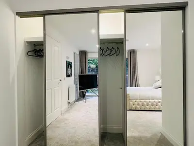 a mirror in a bedroom with a bed and a television at DESIGNER HOUSE - University of Glasgow / Central Glasgow 'Hillhead' West End G12 - Luxurious & Contemporary Detached House / Terrace / Garden / 'electric car charging' Garage Parking in Glasgow