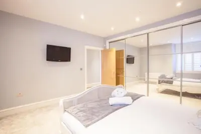 a white bedroom with a bed and a tv at Stylish 2 Bedroom Apartment In Park Circus, West End in Glasgow