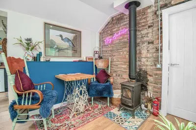 a living room with a brick wall and a wood stove at The Loveshack Lodge Balquhidder in Balquhidder