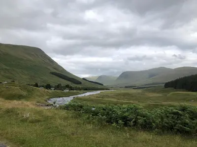 a river in a field with mountains in the background at Ben Grianan in Aberfeldy