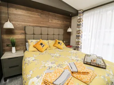 a bedroom with a large yellow bed with pillows at Red Kite Lodge in Crieff