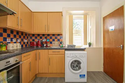 a kitchen with a washing machine and a window at Tinto View Apartment in Carstairs