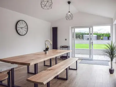 a dining room with a table and a clock on the wall at The Wee White Cottage in Bannockburn
