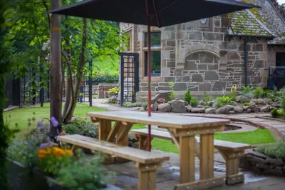 a picnic table with an umbrella in a garden at Stylish Loch Lomond lodge in stunning surroundings in Balloch