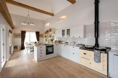 an open kitchen with white cabinets and a dining room at Laverockbank Steading in Buchanty