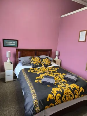 a bedroom with a bed with a black and yellow blanket at The Braveheart House in Edinburgh