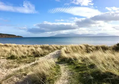a path through a field of grass next to the water at The Lookout in Tighnabruaich