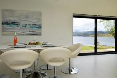 a dining room with a table and chairs and a large window at The Lookout in Tighnabruaich