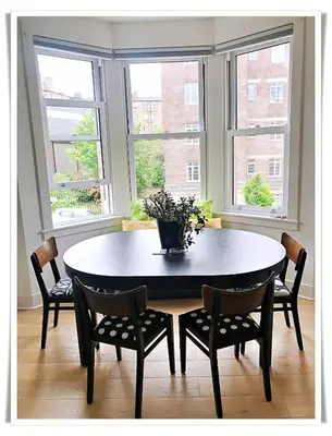 a dining room with a table and two windows at Spacious and modern 2 bedroom flat near the City Centre in Edinburgh