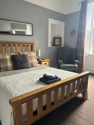 a bedroom with a wooden bed with a robe on it at Callander Meadows in Callander