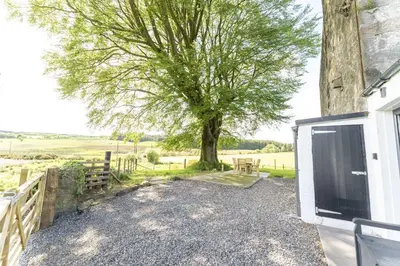 a barn with a tree next to a building at Wilsons Cottage in Falkirk