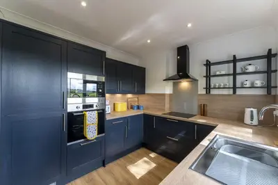 a kitchen with blue cabinets and a sink at Wilsons Cottage in Falkirk