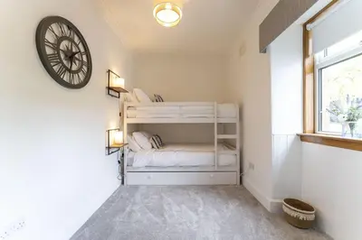 a bedroom with two bunk beds and a clock on the wall at Wilsons Cottage in Falkirk