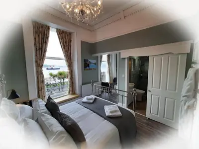 a bedroom with a large bed and a chandelier at Highlander House Boutique Hotel in Rothesay
