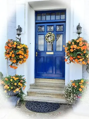 a blue door on a white house with flowers at Highlander House Boutique Hotel in Rothesay