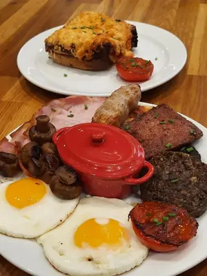 two plates of breakfast food on a wooden table at Highlander House Boutique Hotel in Rothesay