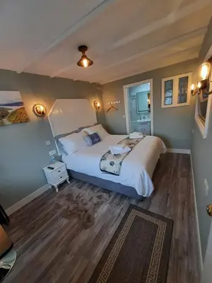 a bedroom with a large white bed and wooden floors at Highlander House Boutique Hotel in Rothesay