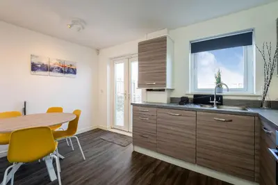 a kitchen with a wooden table and a table and chairs at Modern 3-Bed Family Home Near Glasgow Airport in Bishopton