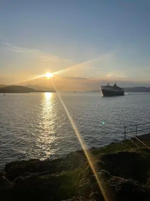 a large ship in the water at sunset at Little bay cabin in Oban