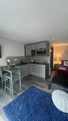 a kitchen and living room with a table and a couch at Little bay cabin in Oban