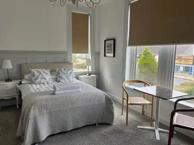 a bedroom with a bed and a table and a window at Giffnock Rooms in Giffnock