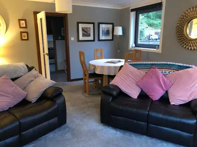 a living room with two leather couches and a table at Heron’s View in Arrochar