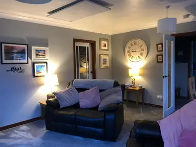 a living room with a couch and a clock on the wall at Heron’s View in Arrochar