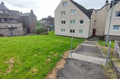 a grassy yard with a building in the background at Lovely 2 Bedroom Modern Ground Floor Flat in Clydebank