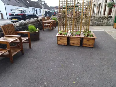 a patio with tables and chairs and plants in wooden crates at Craiglea Thistle in Killin
