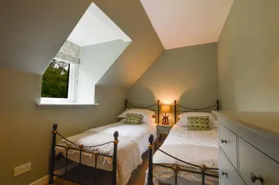 two beds in a attic bedroom with a window at Achanlochan Farm in Taynuilt
