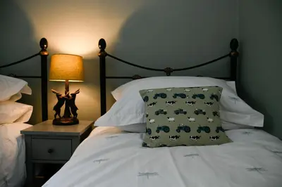 a bedroom with a bed with a pillow and a lamp at Achanlochan Farm in Taynuilt