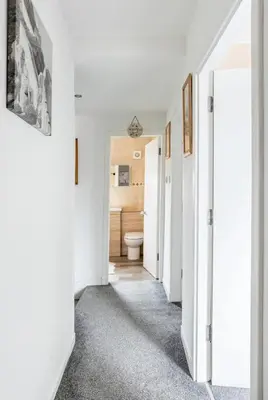 a hallway with a toilet in a white room at Captivating 3 bedroom home with conservatory in Hamilton