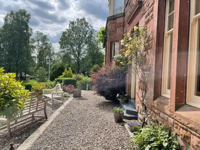 a garden with a bench next to a building at The Bield in Aberfoyle