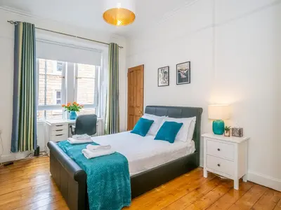 a bedroom with a bed and a chair and a window at Superb 1 Bed Flat in Traditional Victorian Building - Pass the Keys in Edinburgh