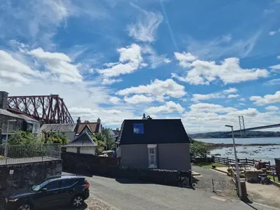 a car parked next to a house next to a river at Three Bridges Waterfront in North Queensferry
